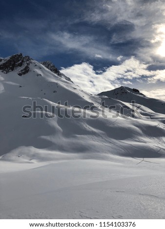 Skiers visible in the distance hiking off piste across landscape amidst Alps in Klosters Switzerland