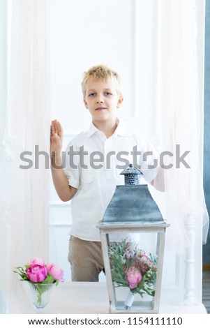 Hansome little boy is standing in a rectangular frame reflection in a mirror. Congratulate to Mom on her birthday, March 8, Mothers Day. Pink bouquet of flowers and large lantern light. Concept banner