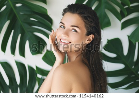 Portrait of young and beautiful woman with perfect smooth skin in tropical leaves. Concept of natural cosmetics and skincare. Royalty-Free Stock Photo #1154140162