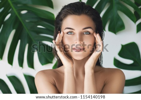 Portrait of young and beautiful woman with perfect smooth skin in tropical leaves. Concept of natural cosmetics and skincare. Royalty-Free Stock Photo #1154140198