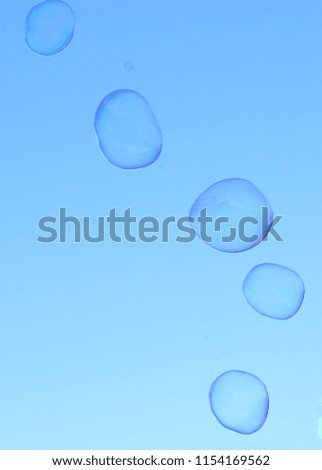 A cluster of soap bubbles in motion, floating in front of a clear blue sky. This photo was taken in Brisbane, Australia. 