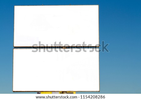 Double white billboard - white blank canvas against the blue sky. Procurement of a billboard with a blank background. City citylights with a blank background shifted to the left. Blank display. Royalty-Free Stock Photo #1154208286
