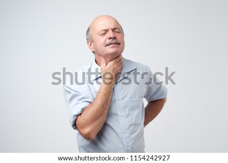 Mature man has a terrible pain in throat because of flu. He lost his voice and can not speak Royalty-Free Stock Photo #1154242927