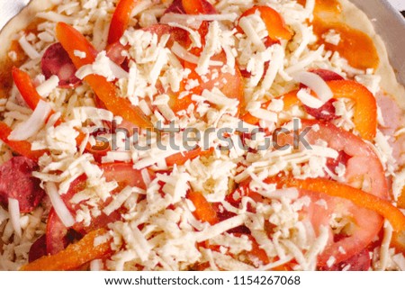 Raw pizzas in wooden table with tomato, onion, pepper and cheese