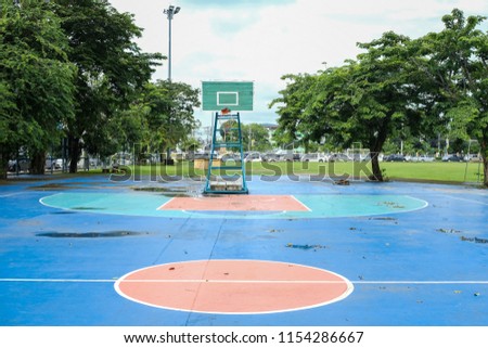 outdoor public basketball court with trees and green grass field around