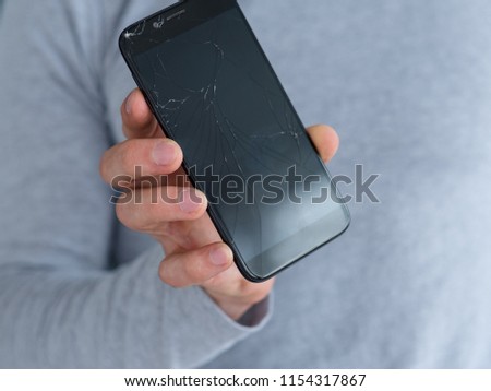 smashed shattered cracked screen. man holding damaged smart phone. mobile devices repair service concept.