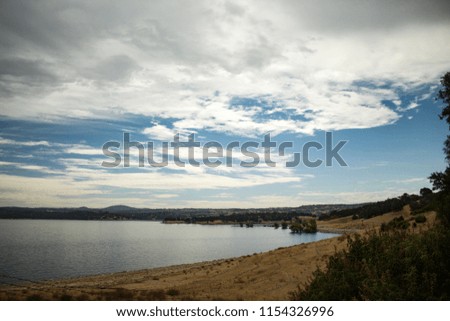 Folsom Lake during summer. California drought. Dead grass. Wide angle lake shore with partly cloudy skies. Freshwater lake.