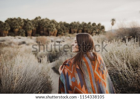 Happy, beautiful hipster traveler girl in gypsy look and windy hair, in desert nature.  Artistic photo of young hipster traveler girl in gypsy look, in Coachella Valley in a desert valley in Souther