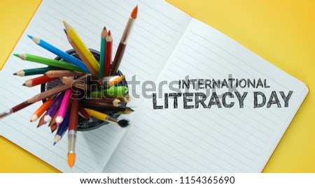 International Literacy Day. School Stationary in Basket on Opened Book Top View Yellow Background Royalty-Free Stock Photo #1154365690