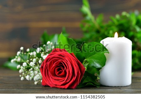 Red rose and white burning candle  