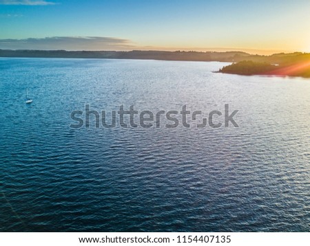 Rupanco Lake, one of the Great lakes in Southern Chile with an amazing aerial view from the drone over Osorno and Puntiagudo Volcanoes surrounded by the water and the trees during the sunset, Chile
