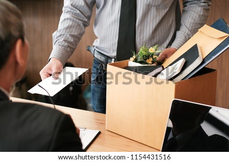 Business man sending resignation letter to boss and Holding Stuff Resign Depress or carrying cardboard box by desk in office Royalty-Free Stock Photo #1154431516