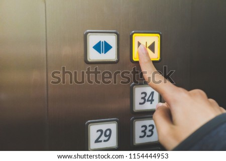 Forefinger pressing the close button in the elevator, selective focus.