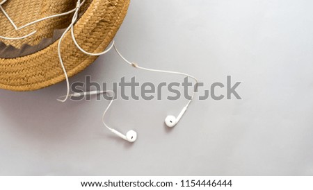 Hat wicker and earphone on gray background