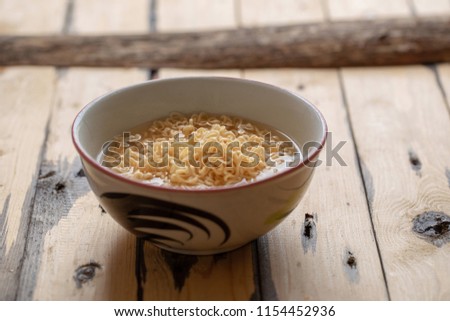 Noodles in bowl on wooden background, selective focus.