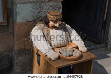 Mannequin Georgian man sitting at a table with a national dish khinkali