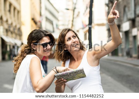 Two women sightseeing around the city with a map