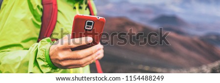 Mobile phone man using his cellphone texting a text message during hiking travel abroad in nature mountains, banner panorama.
