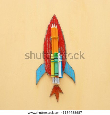 Back to school concept. cardboard rocket cut from paper and painted over wooden yellow background