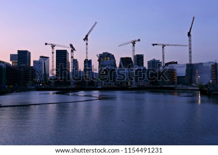 Background of silhouette skyscrapers and cranes under construction. Industrial city landscape at night 