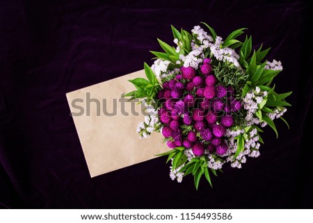 Mockup with paper envelope and flower on dark background. Minimal styled flat lay in dark colors. Top view