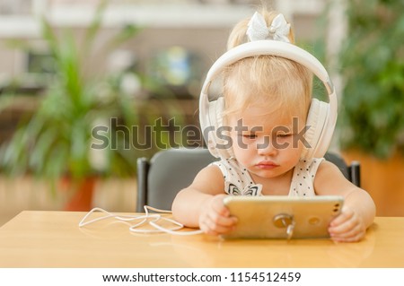little girl watching cartoons on phone in headphones. Space for text