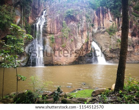 Bright light of Waterfall from cliff on nature background in Thailand.
