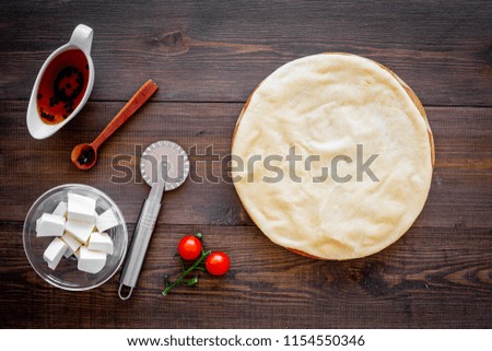 Process of cooking pizza. Pizza Margarita. Raw dough and filling. Cherry tomatoes, cheese mozzarella, spices near knife for pizza on dark wooden background top view mockup copy space