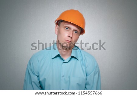 Perplexed builder worker isolated on gray background.
