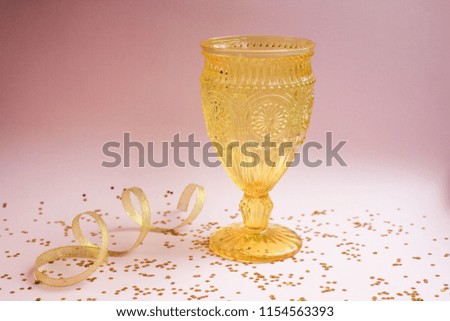 color vintage glasses golden glitter with ribbon on pink table. Colored Vintage Goblets for wine and champagne on white background. 