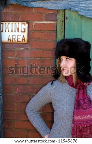 A young Russian girl in front of a wall with a no smoking area sign.