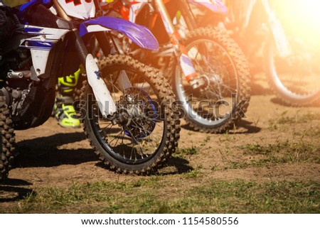 A picture of a biker doing a trick, and jumping into the air.
Motocross Championship. sports fast driving. bike large small.