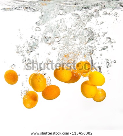 Yellow oranges falling into water causing a splash