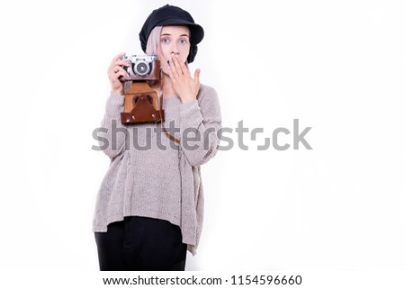 Young woman in black cap with blue lips holds a retro camera in her hands. Isolated on white background