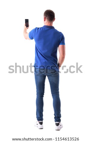 Rear view of modern adult casual man taking photo with smart phone. Full body isolated on white background.