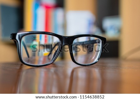 Eyeglasses on a table with bookshelf on background