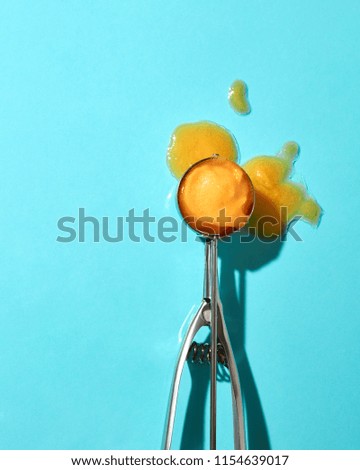 Creative composition from a ball of yellow ice cream on a metal spoon on a blue glass background with shadows. Food modern style.