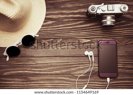 lifestyle flatlay on wooden background retro camera, sunglasses, mobile and hat the view from the top
