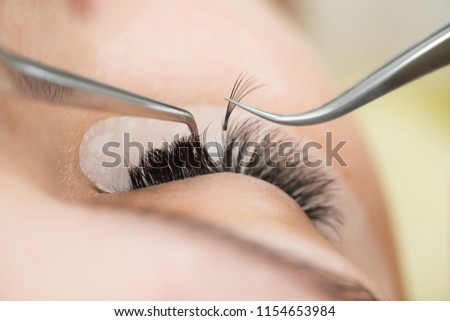 The master builds up large colored eyelashes to the client. Preparation for beauty photography. Creating an image.