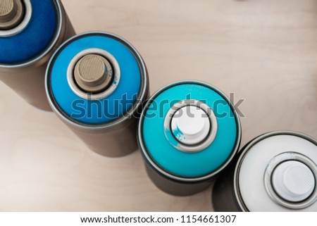 Spray paint dispenser in different colors: shades of blue. Light background