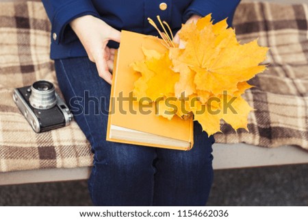 Pregnant young girl sits on a bench and holds a book and yellow 