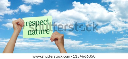 Take notice RESPECT NATURE - female hands holding up a green sign saying RESPECT NATURE against a blue sky wispy clouds  banner background 
