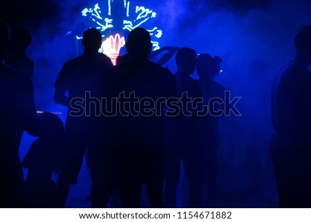 People dance at a nightclub at night in silhouette with different color lights and digital effects
