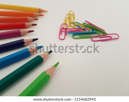 Colored pencils and paper clips laying on a white background, Back to school, School supplies, Office supply, Drawing utensils
