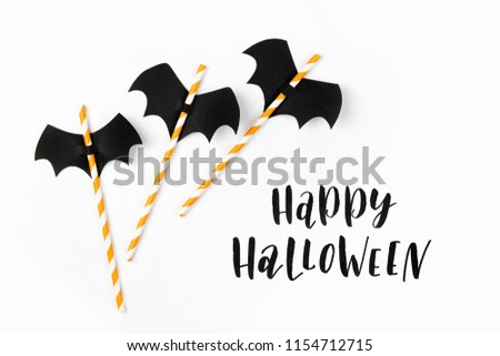 Striped straws with paper bats on white background. Halloween holiday decorations. Flat lay, top view  