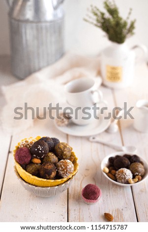 Assorted raw vegan sweet candy gluten-free balls with carob,  coconut and poppy seeds almonds nuts white wooden table