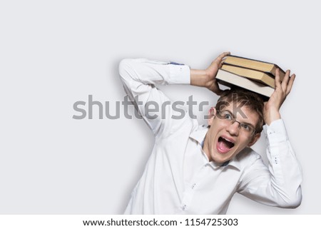 A young man with glasses and a white shirt with books on his head