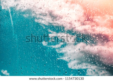 blue sky with pink flare through raindrops on window