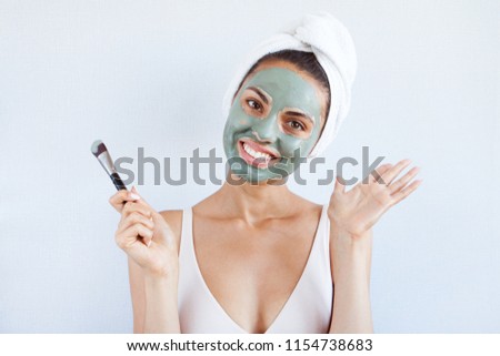 Young beautiful woman in face mask of therapeutic blue mud. Spa treatment, self care and healthy skin. Copy space, white background