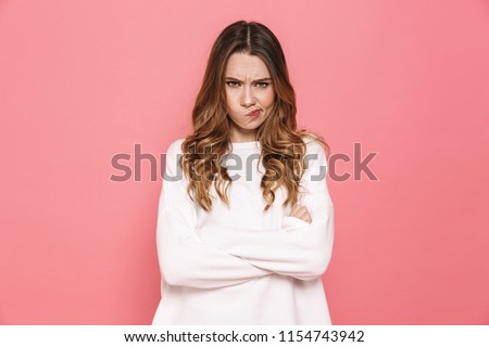 Portrait of an upset young casual girl standing with arms folded isolated over pink background Royalty-Free Stock Photo #1154743942